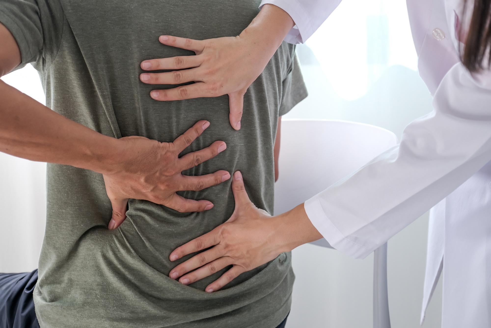 Female doctors hand rehab physical therapy by extending the pain back of patient, t